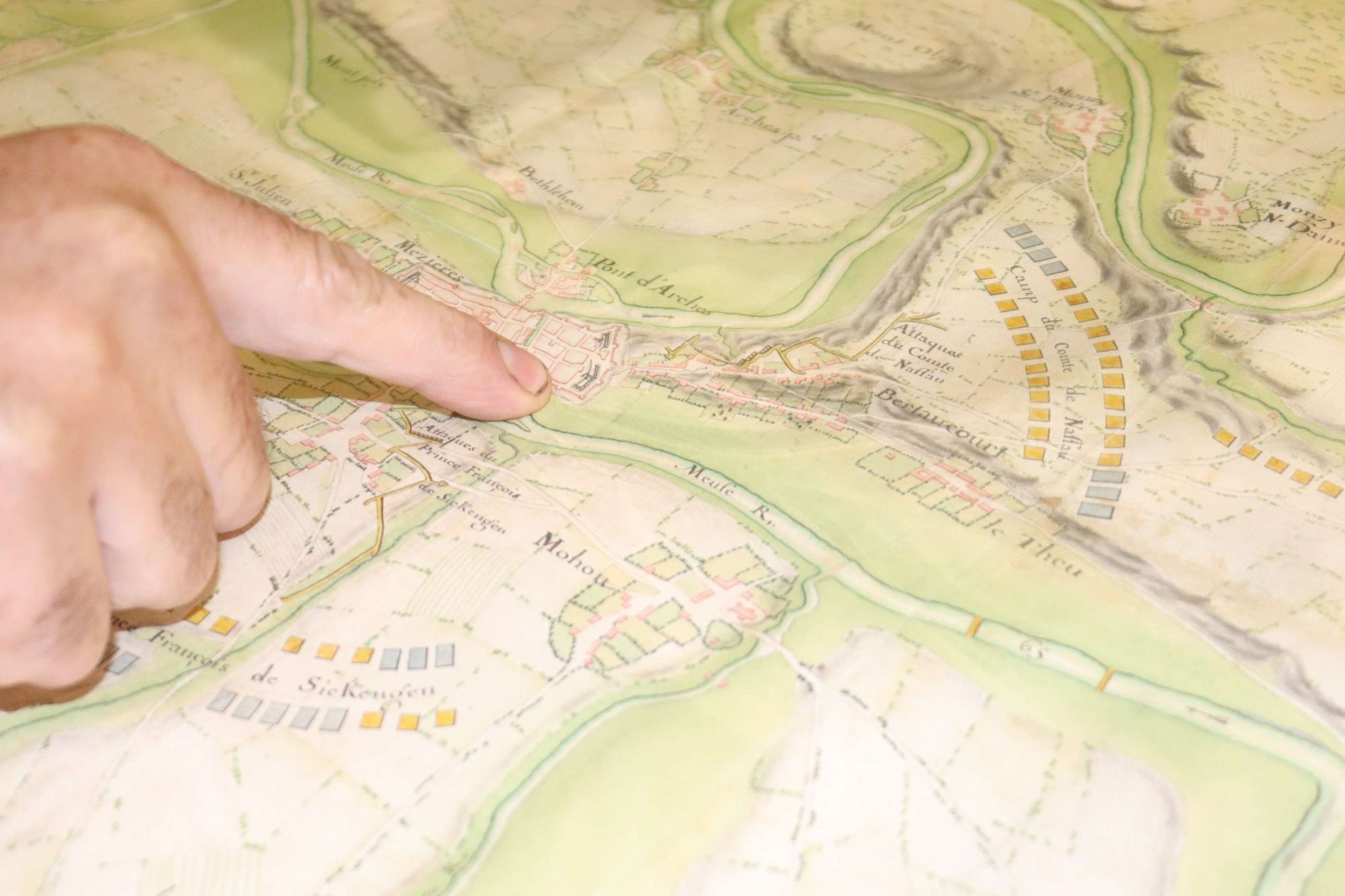 Un doigt pointant l'emplacement des Archives départementales des Ardennes sur un plan de Mézières (©Bruno Gouhoury)